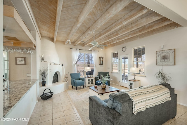 living room featuring beam ceiling, a ceiling fan, wooden ceiling, a fireplace, and light tile patterned floors