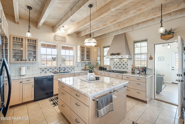 kitchen featuring tasteful backsplash, light brown cabinetry, custom range hood, black dishwasher, and a sink