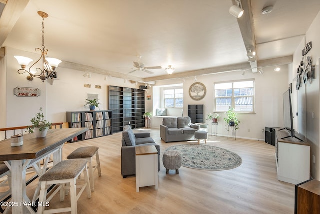 living area featuring ceiling fan with notable chandelier, light wood-type flooring, and baseboards