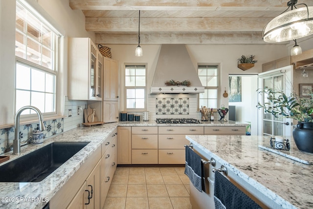 kitchen featuring tasteful backsplash, premium range hood, stainless steel gas cooktop, wooden ceiling, and a sink