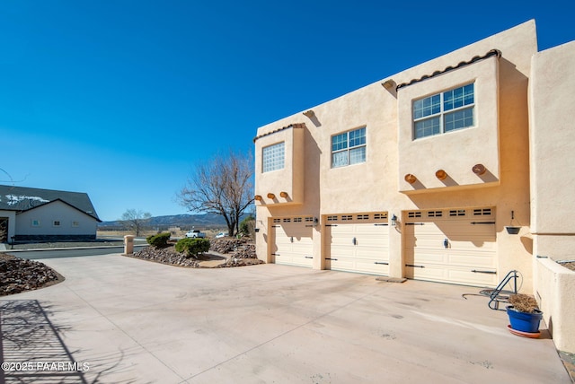 view of property exterior with an attached garage, driveway, and stucco siding