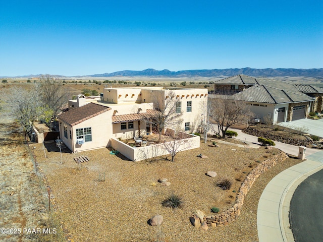 view of front of home featuring a tile roof, concrete driveway, stucco siding, a garage, and a mountain view