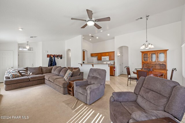 tiled living room featuring a high ceiling and ceiling fan with notable chandelier