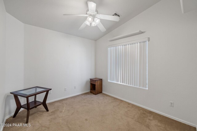 empty room featuring ceiling fan, lofted ceiling, and light carpet