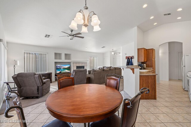 dining room featuring built in shelves, ceiling fan with notable chandelier, light tile patterned flooring, and lofted ceiling