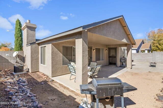 back of property with central AC and a patio