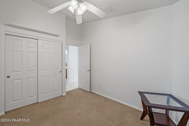 unfurnished bedroom featuring ceiling fan, a closet, and light colored carpet