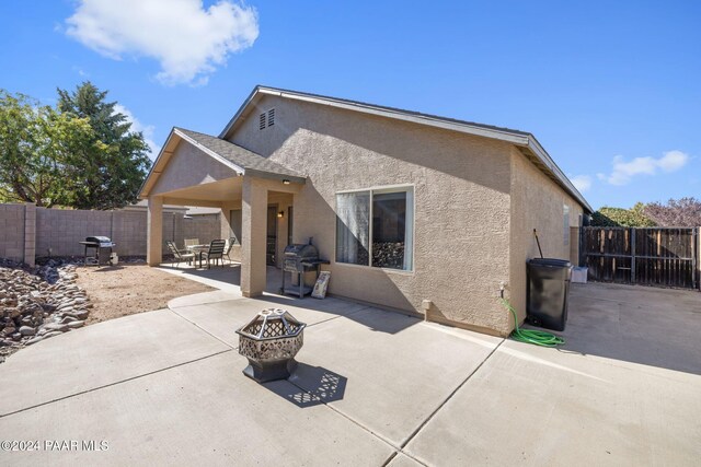 rear view of house with a patio and an outdoor fire pit