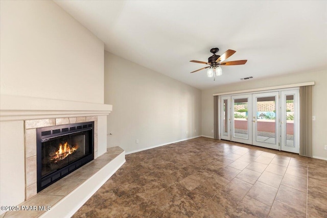 unfurnished living room with a tiled fireplace, lofted ceiling, french doors, and ceiling fan