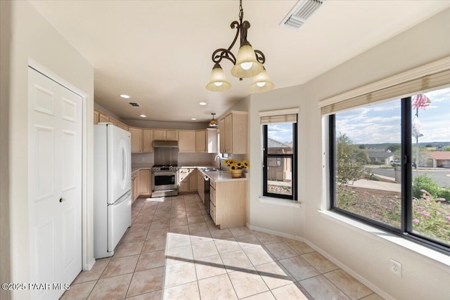 kitchen with stainless steel appliances, light tile patterned flooring, pendant lighting, and light brown cabinetry