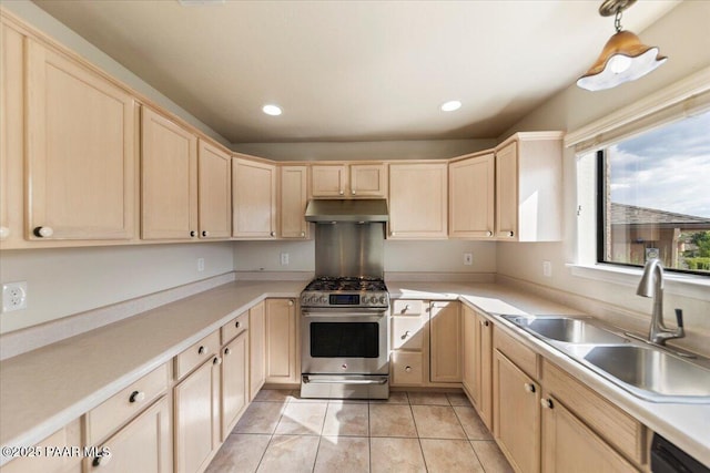 kitchen with sink, high end range, light tile patterned flooring, light brown cabinetry, and decorative light fixtures