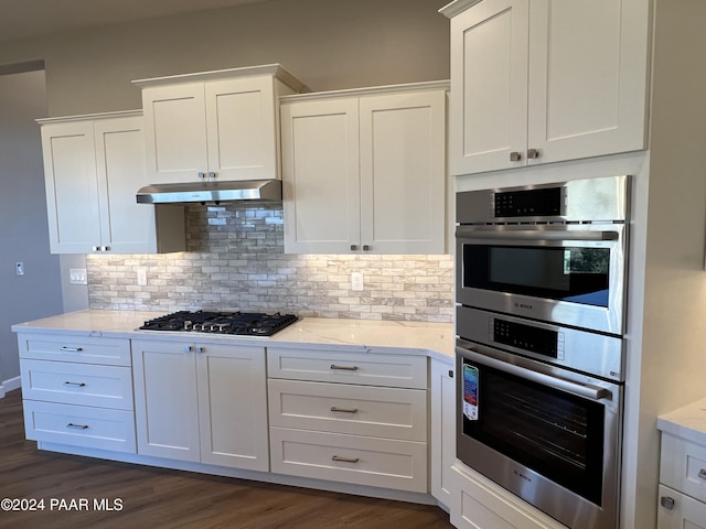 kitchen with light stone counters, dark wood-type flooring, white cabinets, and stainless steel appliances