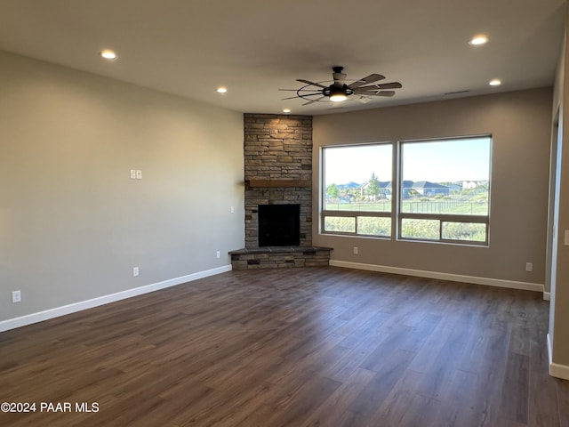 unfurnished living room with ceiling fan, a fireplace, and dark wood-type flooring