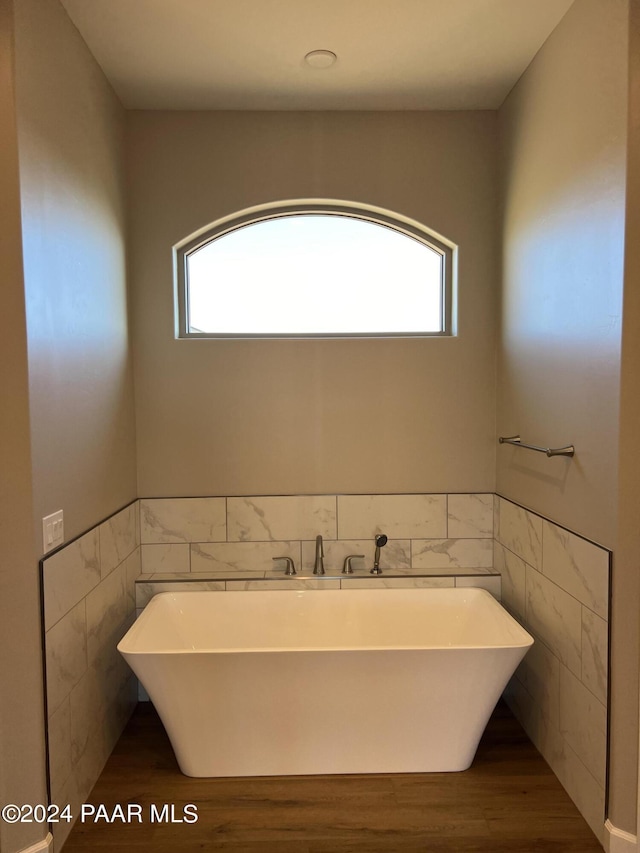 bathroom with a wealth of natural light, tile walls, and hardwood / wood-style flooring