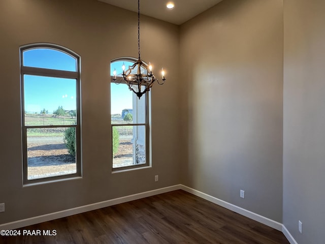 spare room featuring a chandelier and dark hardwood / wood-style flooring