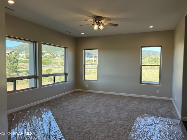 carpeted empty room featuring ceiling fan and a healthy amount of sunlight