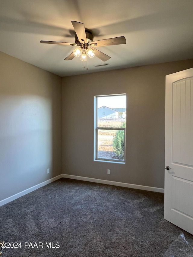 spare room featuring ceiling fan and dark carpet