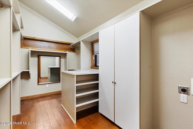 walk in closet with light hardwood / wood-style floors and lofted ceiling