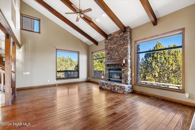 unfurnished living room with high vaulted ceiling, ceiling fan, a fireplace, beamed ceiling, and wood-type flooring