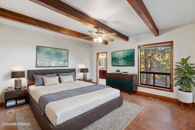 bedroom with beam ceiling, light wood-type flooring, ceiling fan, and connected bathroom