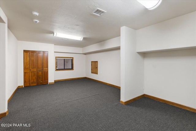 basement with a textured ceiling and dark carpet