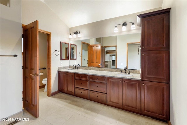 bathroom featuring vanity, toilet, and lofted ceiling