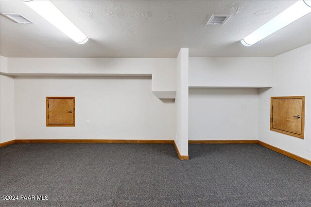 basement with dark colored carpet and a textured ceiling