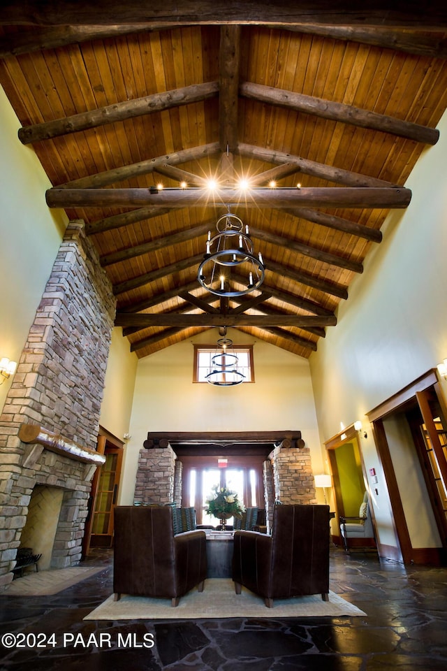 interior space with a stone fireplace, high vaulted ceiling, beamed ceiling, wooden ceiling, and an inviting chandelier