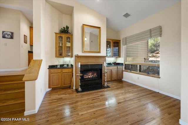 living room with a premium fireplace, vaulted ceiling, and light hardwood / wood-style flooring