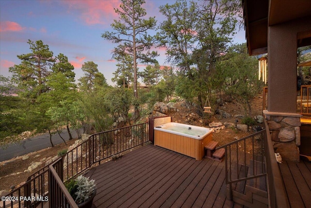 deck at dusk featuring a hot tub