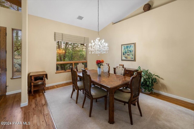 dining space featuring wood-type flooring, a chandelier, and vaulted ceiling