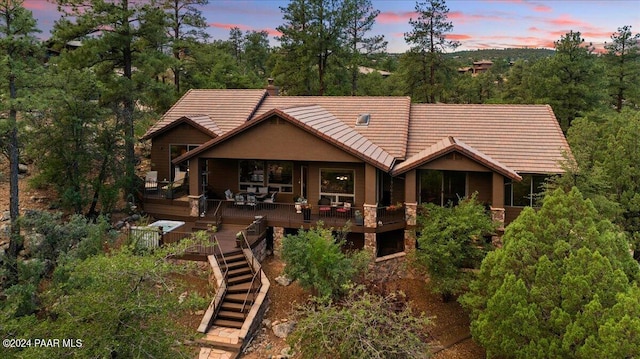 back house at dusk featuring a deck