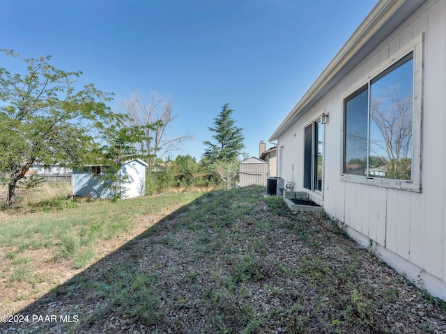 view of yard featuring a storage shed and central air condition unit