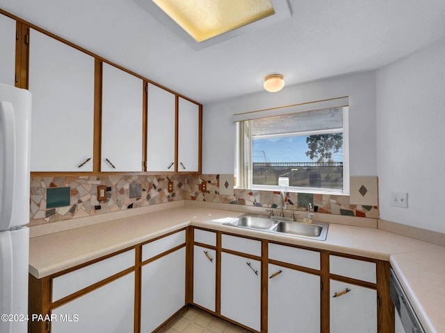 kitchen with white fridge, white cabinetry, sink, and tasteful backsplash