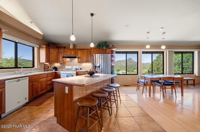 435 Fairway View Dr, Prescott, AZ 86303 - kitchen with white appliances, light tile patterned flooring, under cabinet range hood, brown cabinets, and light countertops