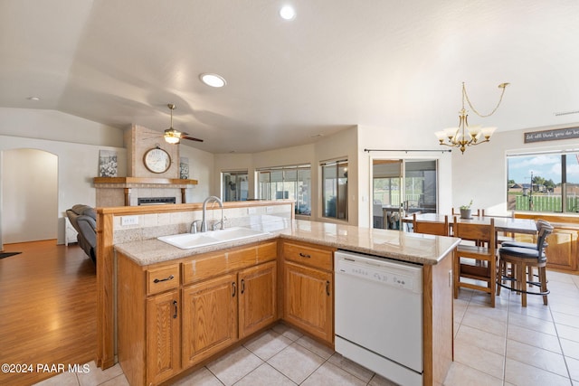 kitchen featuring pendant lighting, a tiled fireplace, dishwasher, lofted ceiling, and light tile patterned flooring