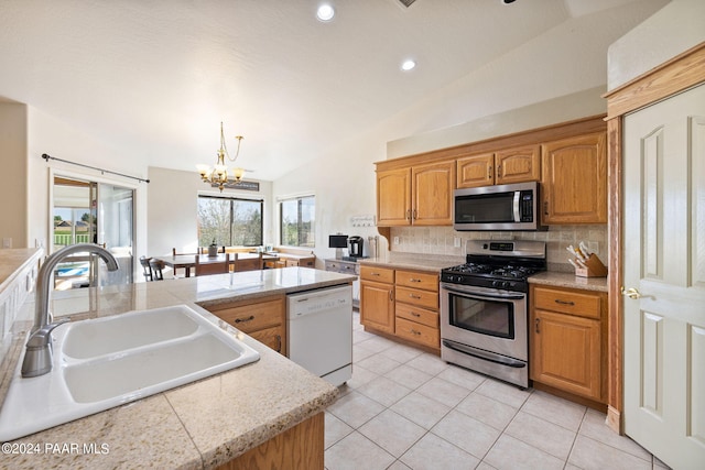 kitchen featuring sink, hanging light fixtures, plenty of natural light, vaulted ceiling, and appliances with stainless steel finishes