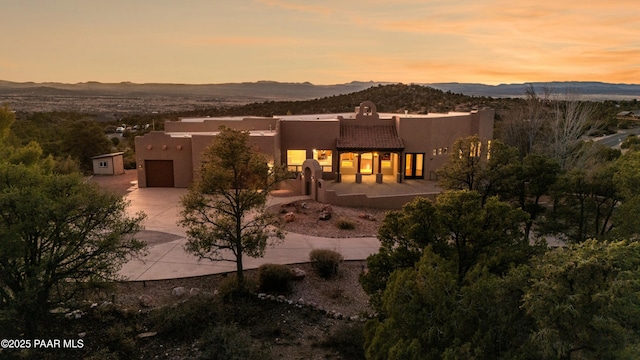 view of front facade with a mountain view, driveway, and stucco siding