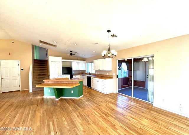 kitchen featuring butcher block counters, hanging light fixtures, a kitchen island, vaulted ceiling, and white cabinets