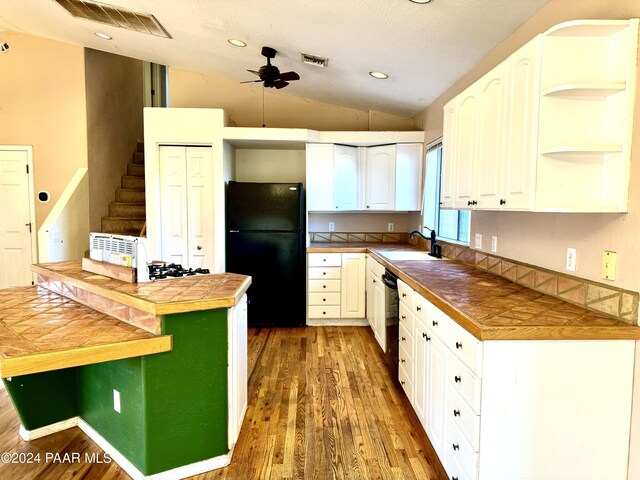 kitchen featuring dark wood-type flooring, sink, black appliances, tile countertops, and lofted ceiling