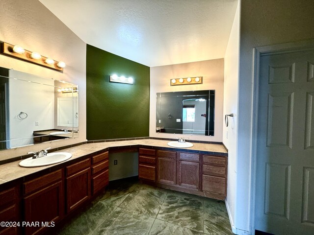 bathroom featuring a textured ceiling, vanity, and vaulted ceiling