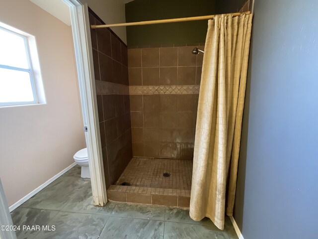 bathroom with a shower with shower curtain, tile patterned flooring, and toilet