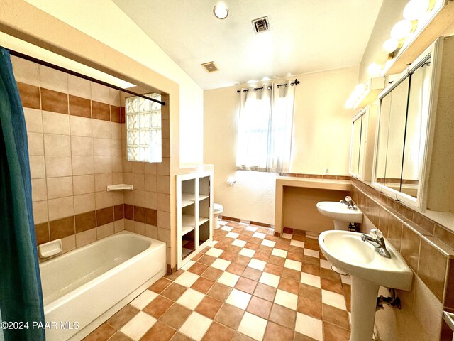 full bathroom featuring decorative backsplash, tiled shower / bath combo, sink, toilet, and lofted ceiling