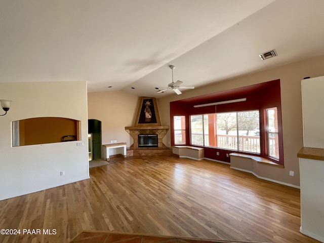 unfurnished living room featuring a fireplace, wood-type flooring, vaulted ceiling, and ceiling fan