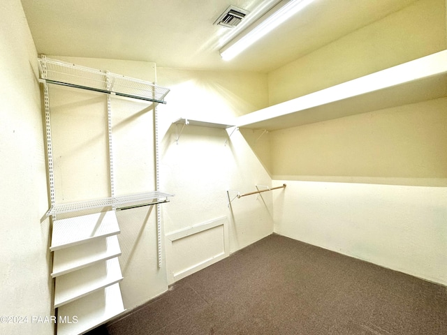 walk in closet featuring dark carpet and lofted ceiling