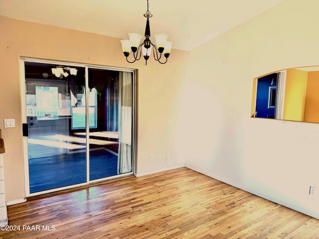 spare room with hardwood / wood-style floors and an inviting chandelier