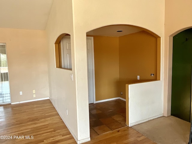 hallway with hardwood / wood-style floors and lofted ceiling