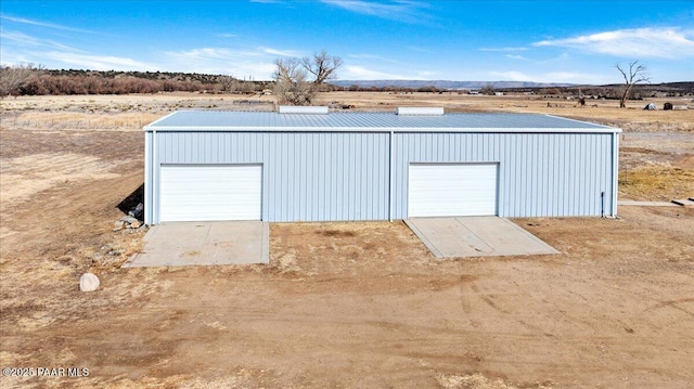 view of outbuilding featuring a rural view, an outdoor structure, and a mountain view