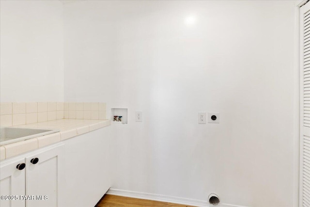 washroom featuring hookup for a washing machine, light wood-style floors, hookup for an electric dryer, and cabinet space