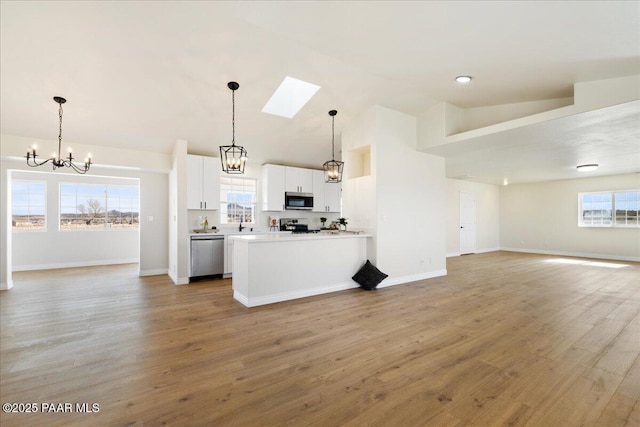kitchen with pendant lighting, stainless steel appliances, light countertops, open floor plan, and white cabinetry